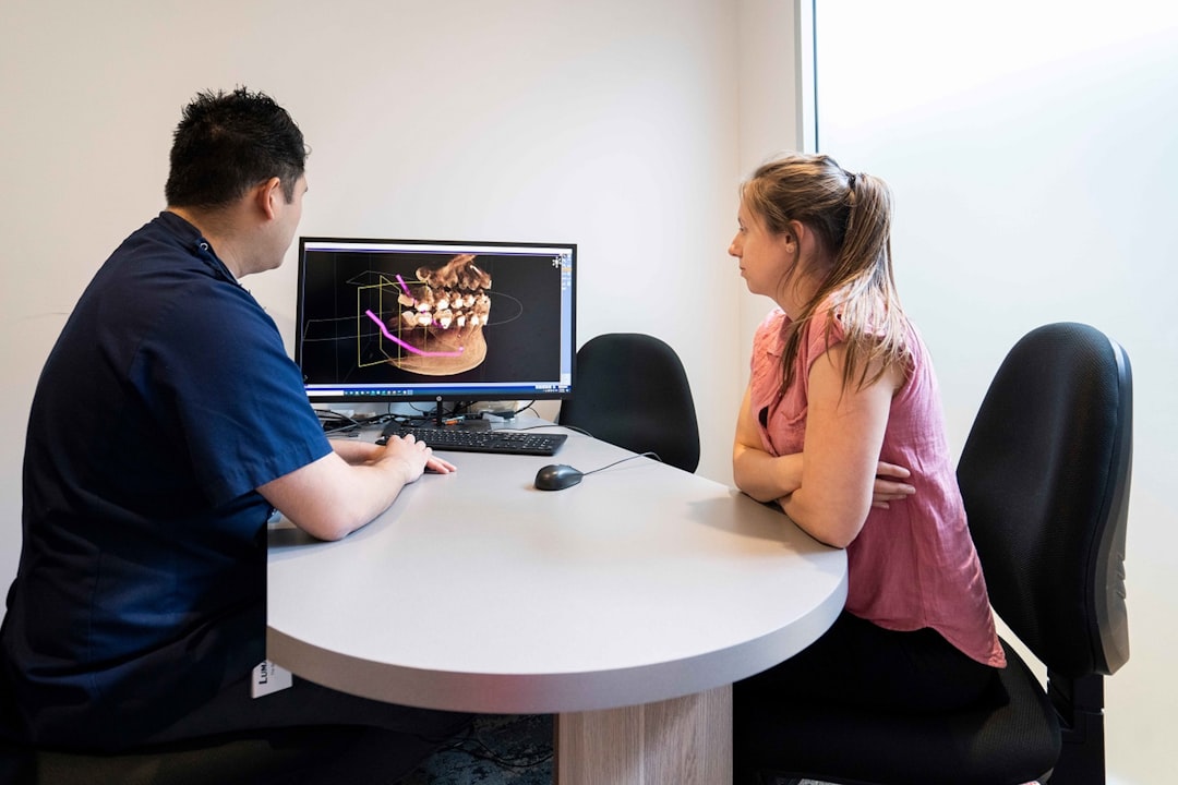 A man and a woman sitting at a table looking at a computer screen