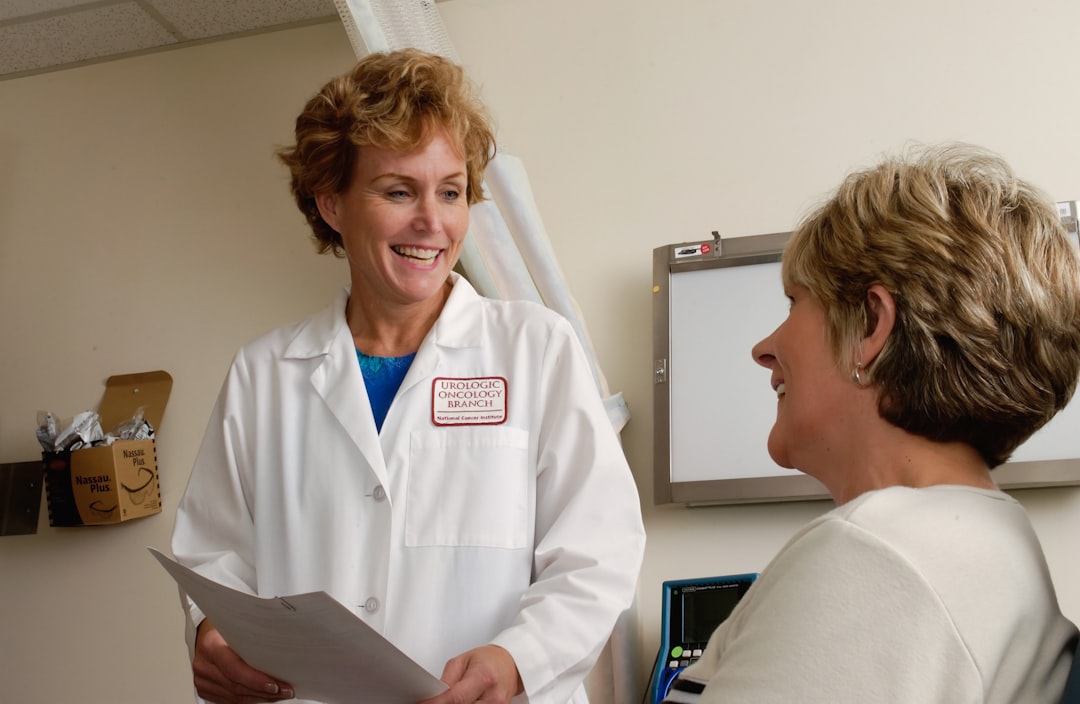A smiling doctor in a white coat talking to a patient in a clinic